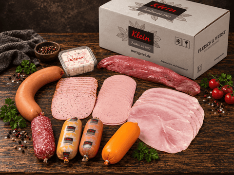 Probierpaket mit Fleischsalat, Würstchen und Aufschnitt vor einem Versandkarton