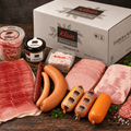 Wurstpaket mit Aufschnitt, Würstchen und Wurst im Glas vor einem Versandkarton