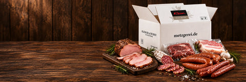Fleisch- und Wurstauswahl neben einem Versandkarton der Metzgerei Klein